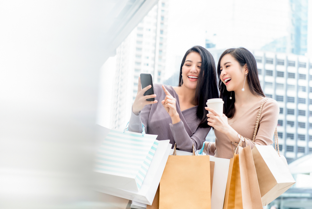 Mulheres animadas em shopping depois de uma loja usar uma das estratégias de como aumentar as vendas