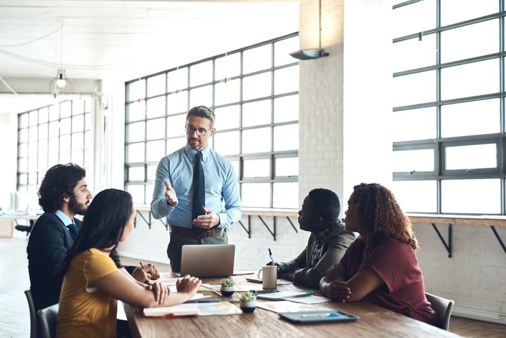 Líder em uma reunião com sua equipe, exemplificando diferentes estilos de liderança e comunicação no ambiente de trabalho.