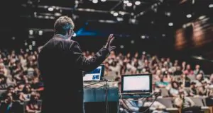 Homem em auditório dando palestra para um grande público