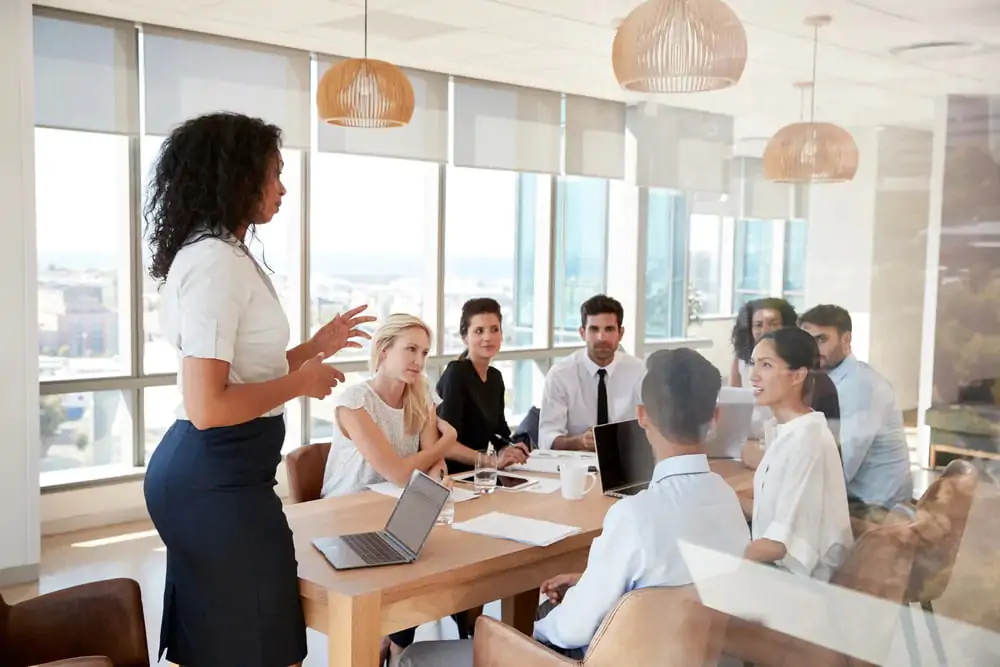 mulher dando palestra para funcionários de empresa em sala de reunião