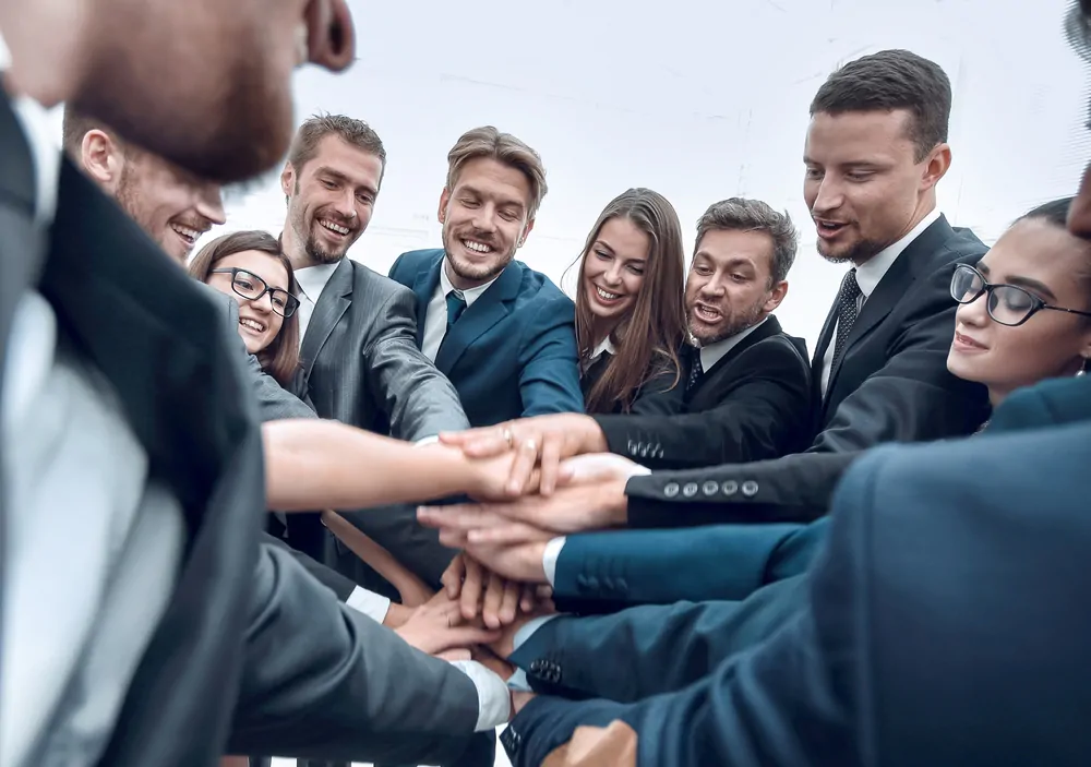 Equipe coloca as mãos uma em cima da outra.