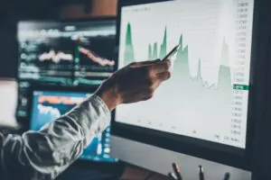 Apontando com caneta para tela de computador com graficos